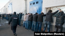 Russian police detain migrant workers during a raid at a vegetable warehouse complex in the Biryulyovo district of Moscow October 14, 2013. 